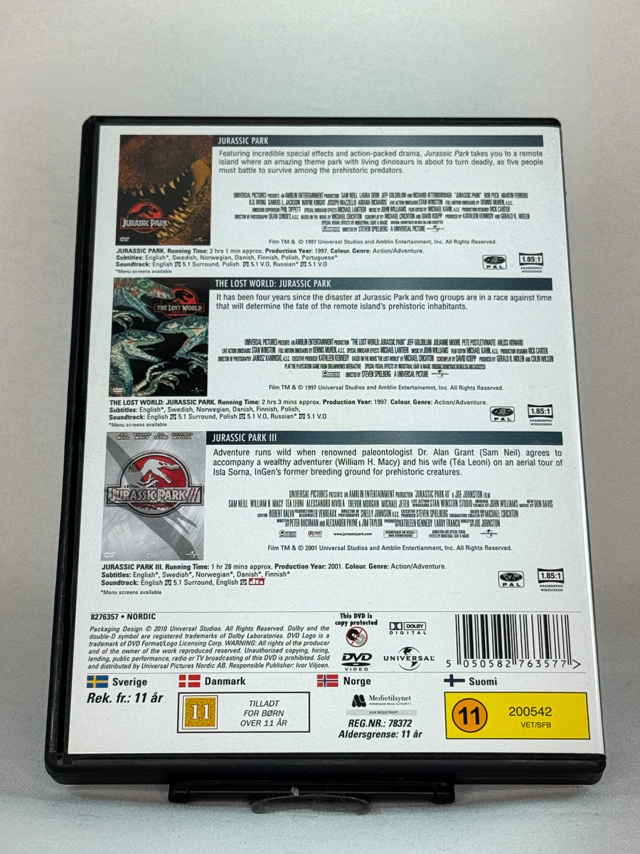 Bakside av DVD-cover til Jurassic Park Trilogy – The Complete Collection – inkluderer Jurassic Park, The Lost World og Jurassic Park III, brukt originalsamling på DVD hos Brukbar Film.