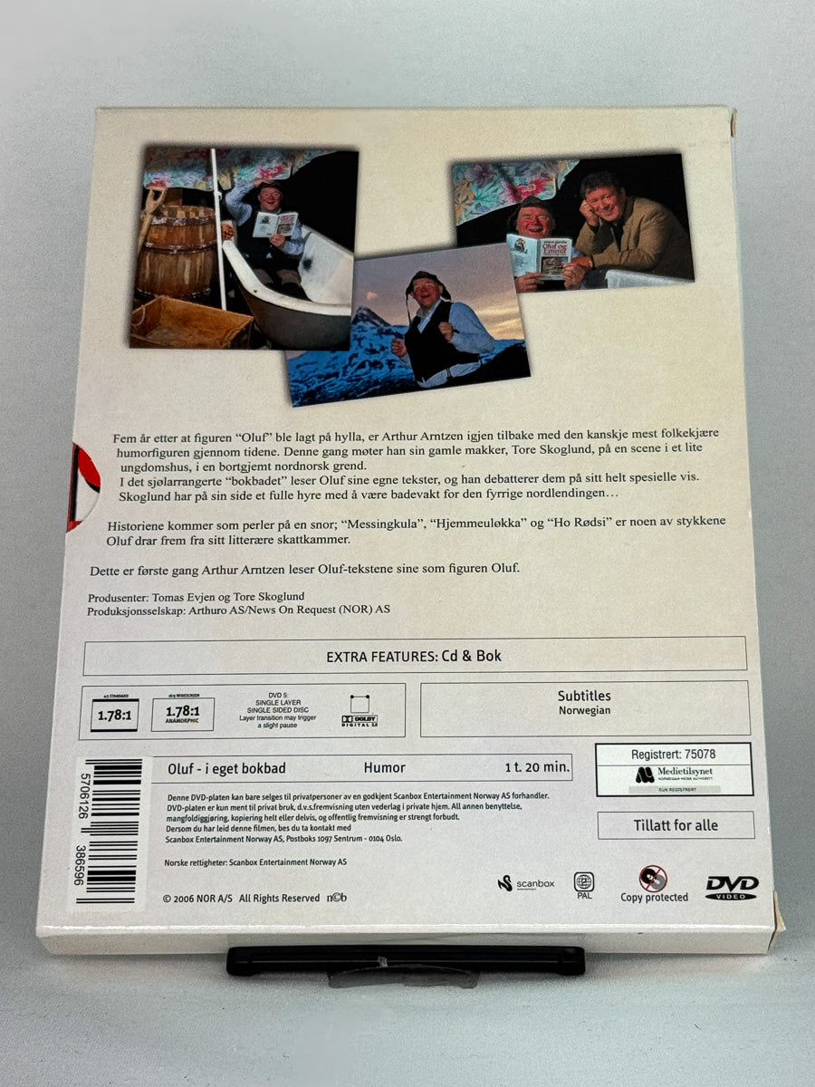 Bakside av samleboksen Oluf i eget bokbad – inneholder både film, lydspor og bok, et unikt norsk humorprodukt tilgjengelig hos Brukbar Film.