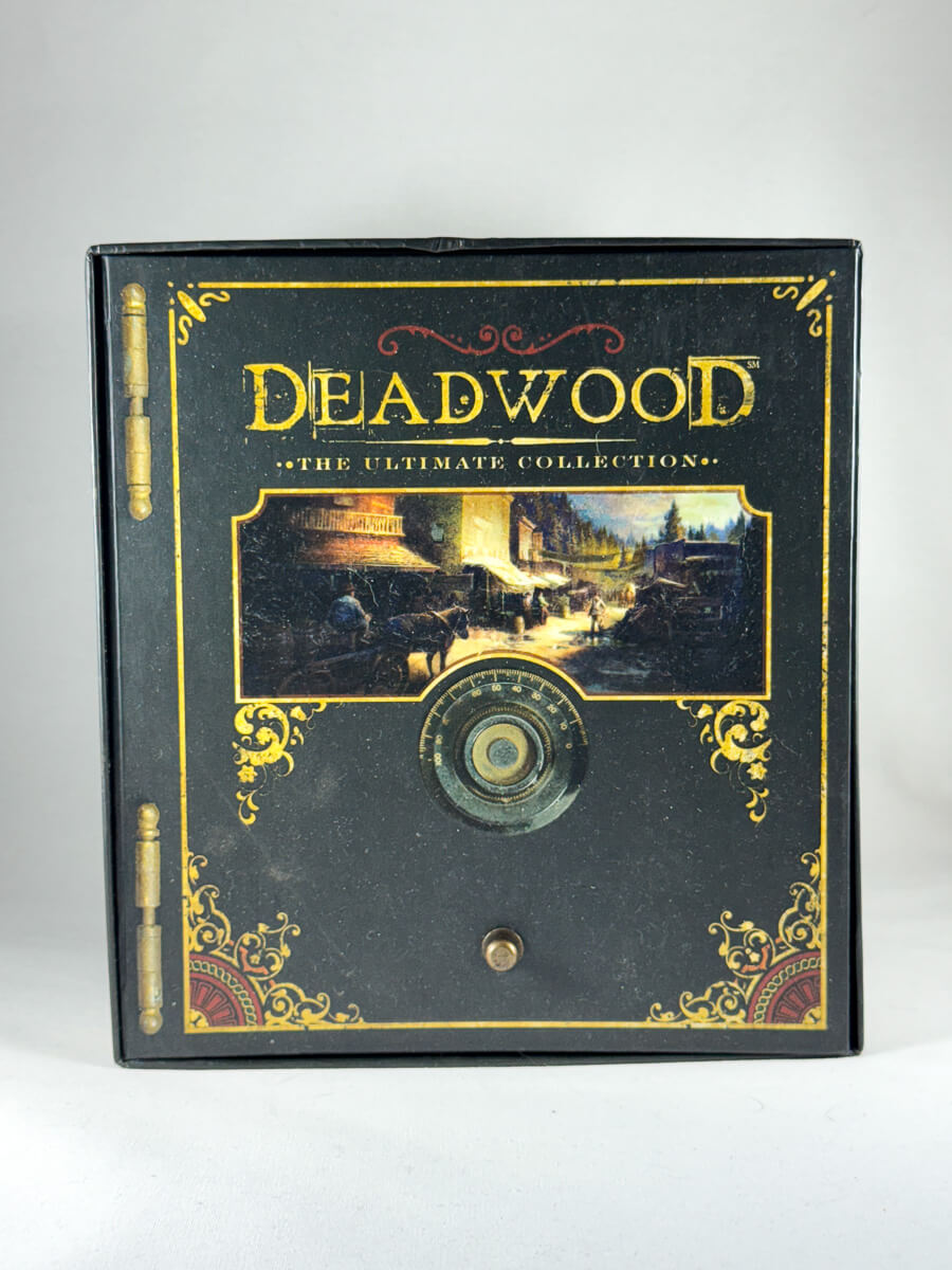 Forside av samleboksen Deadwood – The Ultimate Collection – komplett westernserie i dekorativ safe-boks med alle tre sesonger, kortstokk og pokerchips inkludert, brukt DVD-utgave tilgjengelig hos Brukbar Film.