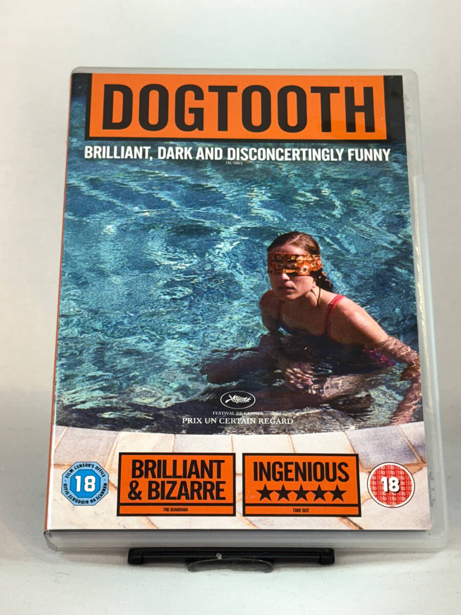 Forside av DVD-cover til Dogtooth (2009) – psykologisk drama fra regissør Yorgos Lanthimos, vinner av Prix Un Certain Regard i Cannes – brukt DVD hos Brukbar Film.