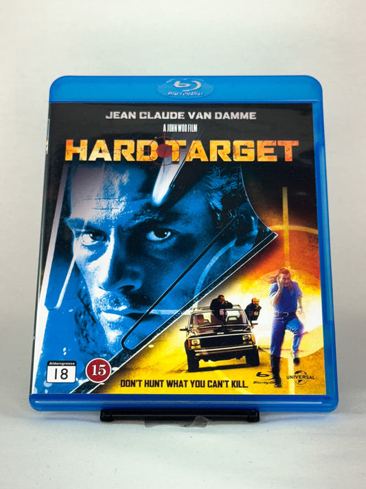 Forside av Blu-ray-cover til Hard Target – actionfilm med Jean-Claude Van Damme regissert av John Woo, fylt med eksplosjoner og høyoktan kamp, brukt Blu-ray hos Brukbar Film.