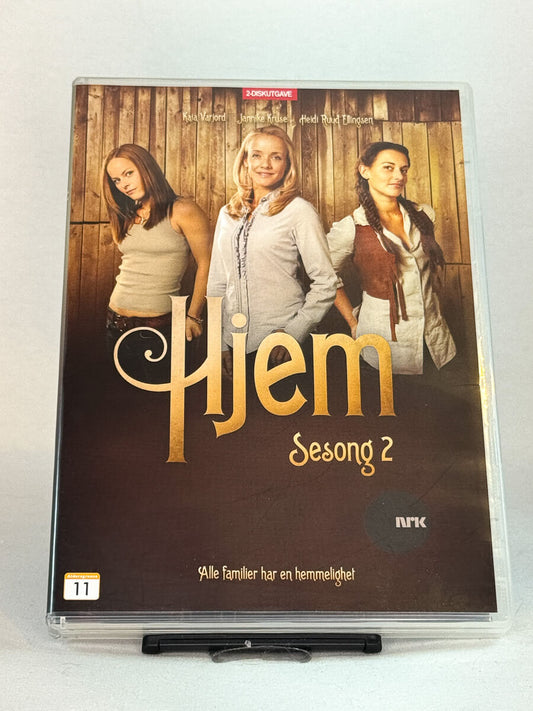 Forside av DVD-cover til Hjem – Sesong 2 – NRKs dramaserie med Kaia Varjord, Janne Kruse og Heidi Ruud Ellingsen, brukt norsk TV-serie på DVD hos Brukbar Film.