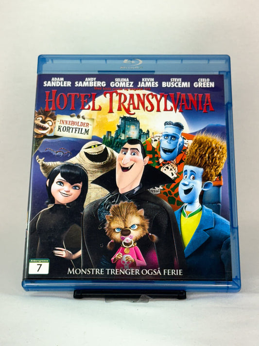 Forside av Blu-ray-cover til Hotel Transylvania – morsom animasjonsfilm der Dracula driver hotell for monstre, med stemmer av Adam Sandler og Selena Gomez, brukt Blu-ray hos Brukbar Film.