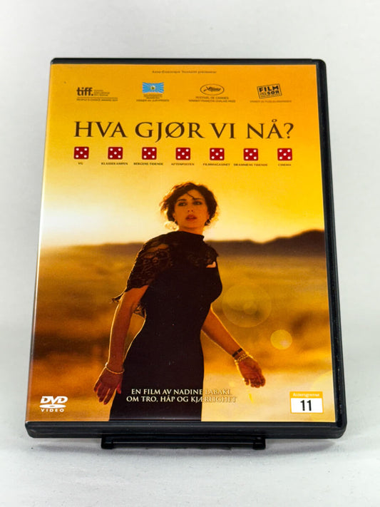Forside av DVD-cover til Hva gjør vi nå? (originaltittel: Et maintenant, on va où?) – libanesisk dramakomedie regissert av Nadine Labaki, hos Brukbar Film.