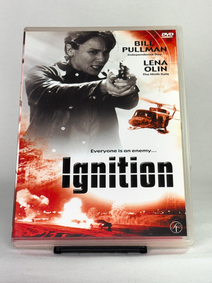 Forside av DVD-cover til Ignition med Bill Pullman og Lena Olin – intens actionthriller om konspirasjon og maktspill – brukt DVD-film tilgjengelig hos Brukbar Film.