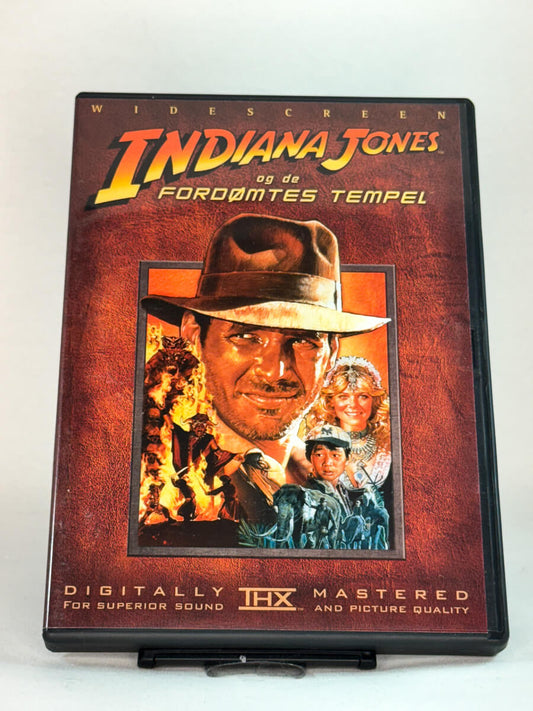 Forside av DVD-cover til Indiana Jones og de fordømtes tempel (originaltittel: Indiana Jones and the Temple of Doom) – mørkere, intens oppfølger i den ikoniske serien, brukt actioneventyr på DVD hos Brukbar Film.