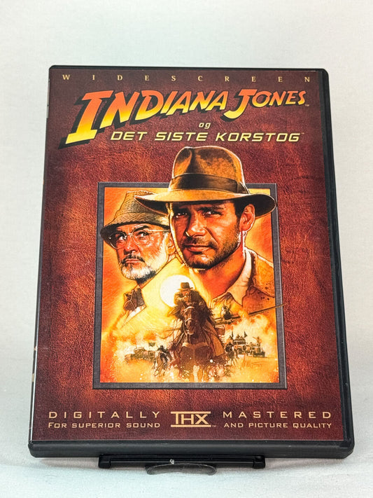 Forside av DVD-cover til Indiana Jones og det siste korstog (originaltittel: Indiana Jones and the Last Crusade) – Harrison Ford og Sean Connery i et eventyrlig actionkapittel, brukt film på DVD hos Brukbar Film.