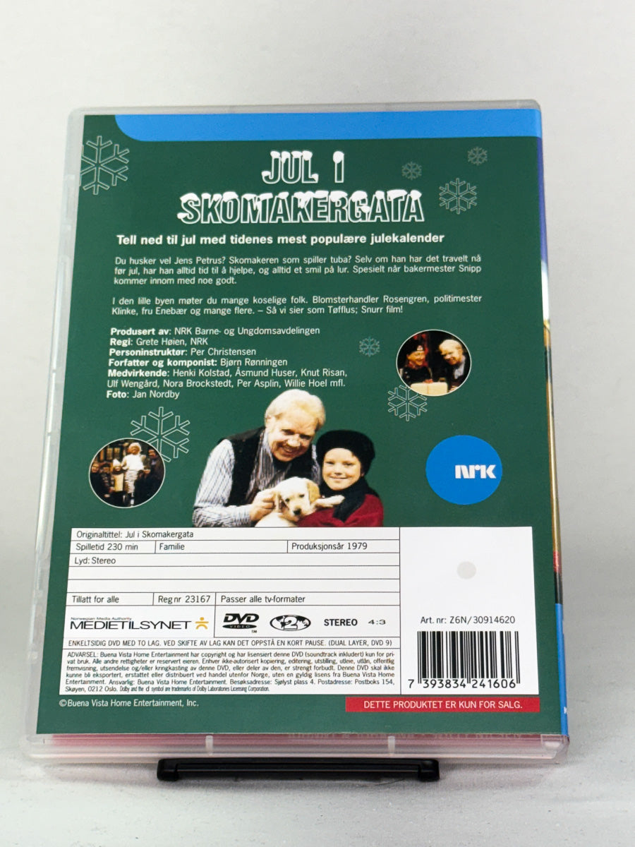 Bakside av DVD-cover til Jul i Skomakergata 1 – viser episodeliste og omtale av den folkekjære julekalenderen fra NRK – brukt DVD hos Brukbar Film.