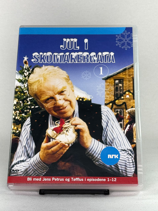 Forside av DVD-cover til Jul i Skomakergata 1 – klassisk NRK-julekalender med Henki Kolstad som Jens Petrus i episodene 1–12 – brukt DVD hos Brukbar Film.