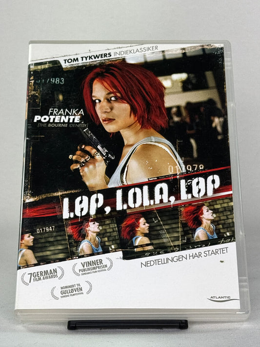 Forside av DVD-cover til Løp, Lola, løp (Run Lola Run) – tysk actionthriller med Franka Potente regissert av Tom Tykwer – brukt DVD tilgjengelig hos Brukbar Film.