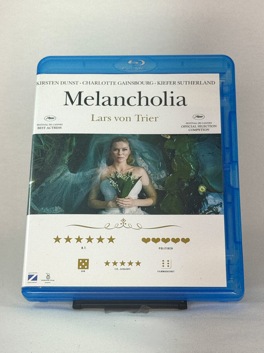 Forside av Blu-ray-cover til Melancholia – Lars von Triers apokalyptiske drama med Kirsten Dunst og Charlotte Gainsbourg, brukt Blu-ray hos Brukbar Film.