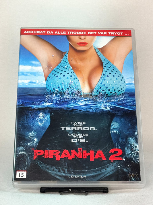 Forside av DVD-cover til Piranha 2 – blodig og humoristisk skrekkoppfølger full av undervannsterror og over-the-top action, brukt DVD tilgjengelig hos Brukbar Film.