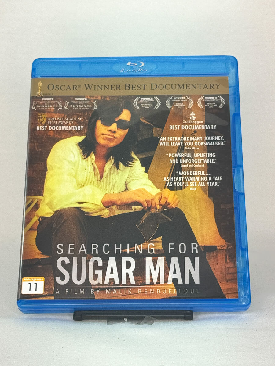 Forside av Blu-ray-cover til Searching for Sugar Man – Oscar-vinnende dokumentar om musikeren Sixto Rodriguez, brukt Blu-ray hos Brukbar Film.
