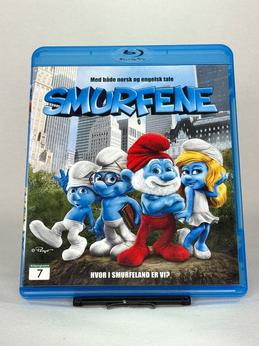 Forside av Blu-ray-cover til Smurfene – eventyrlig familiefilm der de blå figurene havner midt i New York, med både norsk og engelsk tale, brukt Blu-ray hos Brukbar Film.