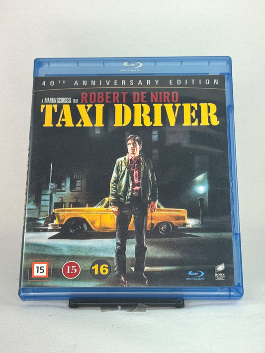 Forside av Blu-ray-cover til Taxi Driver – Martin Scorseses mørke mesterverk med Robert De Niro i en ikonisk rolle, brukt Blu-ray tilgjengelig hos Brukbar Film.