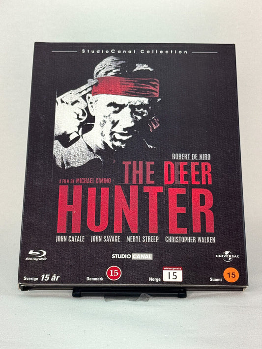 Forside av Blu-ray-cover til The Deer Hunter – brukt krigsdrama på Blu-ray med Robert De Niro, selges hos Brukbar Film.