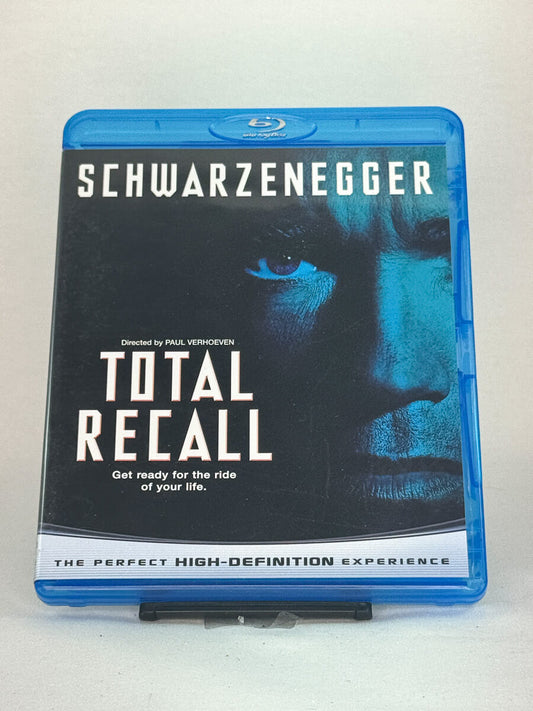 Forside av Blu-ray-cover til Total Recall – sci-fi-klassiker regissert av Paul Verhoeven, med Arnold Schwarzenegger i en intens futuristisk actionrolle, brukt Blu-ray hos Brukbar Film.